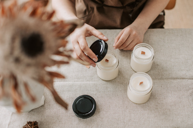 Finished container candles with wooden wicks on a linen table