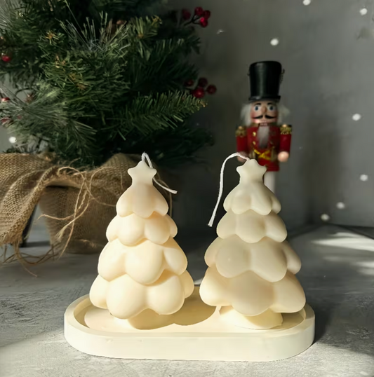 Two tree-shaped candles on a base with a Christmas tree and nutcracker in the background.