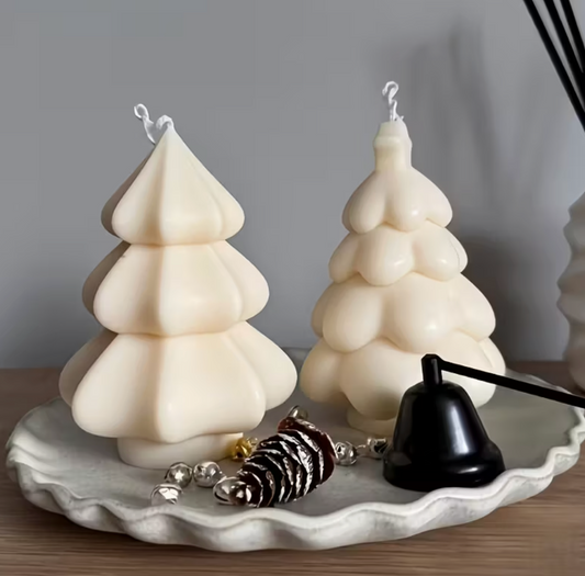 Two tree-shaped candles on a decorative plate with small ornaments against a gray background