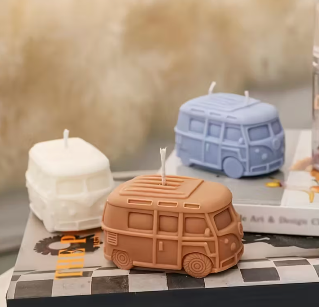 Three van-shaped candles on a checkered surface with a blurred background