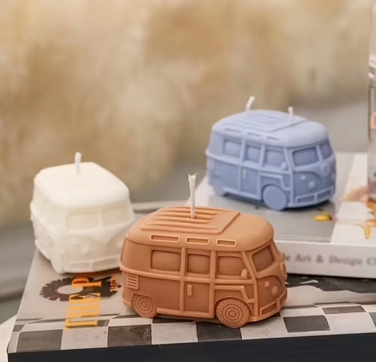 Three van-shaped candles on a checkered surface with a blurred background